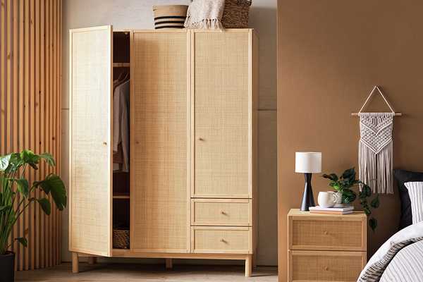 A three-door wardrobe with two drawers near a bedside table.